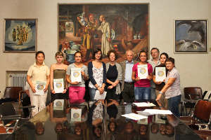 Foto di gruppo della cerimonia di consegna borse di studio Camprini Malmerendi 2010/2011, presso la Sala Nera del Comune di Cesena, alla presenza di Francesco Malmerendi (figlio di Giannetto), l'Assessore del Comune di Cesena Simona Benedetti, la Presidente ASP Elide Urbini, il Dirigente ASP Massimo Comandini e gli studenti premiati. Sullo sfondo il dipinto "Mario Morigi e Malmerendi nella fabbrica di ceramiche" del 1933