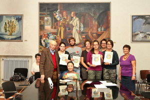 Foto di gruppo della cerimonia di consegna borse di studio Camprini Malmerendi 2011/2012, presso la Sala Nera del Comune di Cesena, alla presenza di Francesco Malmerendi (figlio di Giannetto), l'Assessore del Comune di Cesena Simona Benedetti, la Presidente ASP Elide Urbini e gli studenti premiati. Sullo sfondo il dipinto "Mario Morigi e Malmerendi nella fabbrica di ceramiche" del 1933